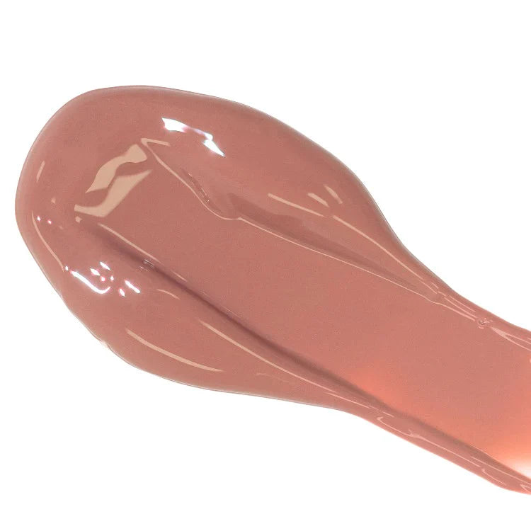 Smear of glossy nude lipstick on white background.